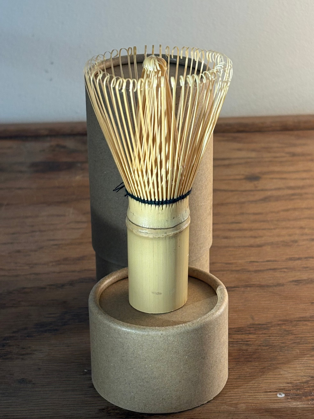 Bamboo whisk on a wooden stand against a plain background