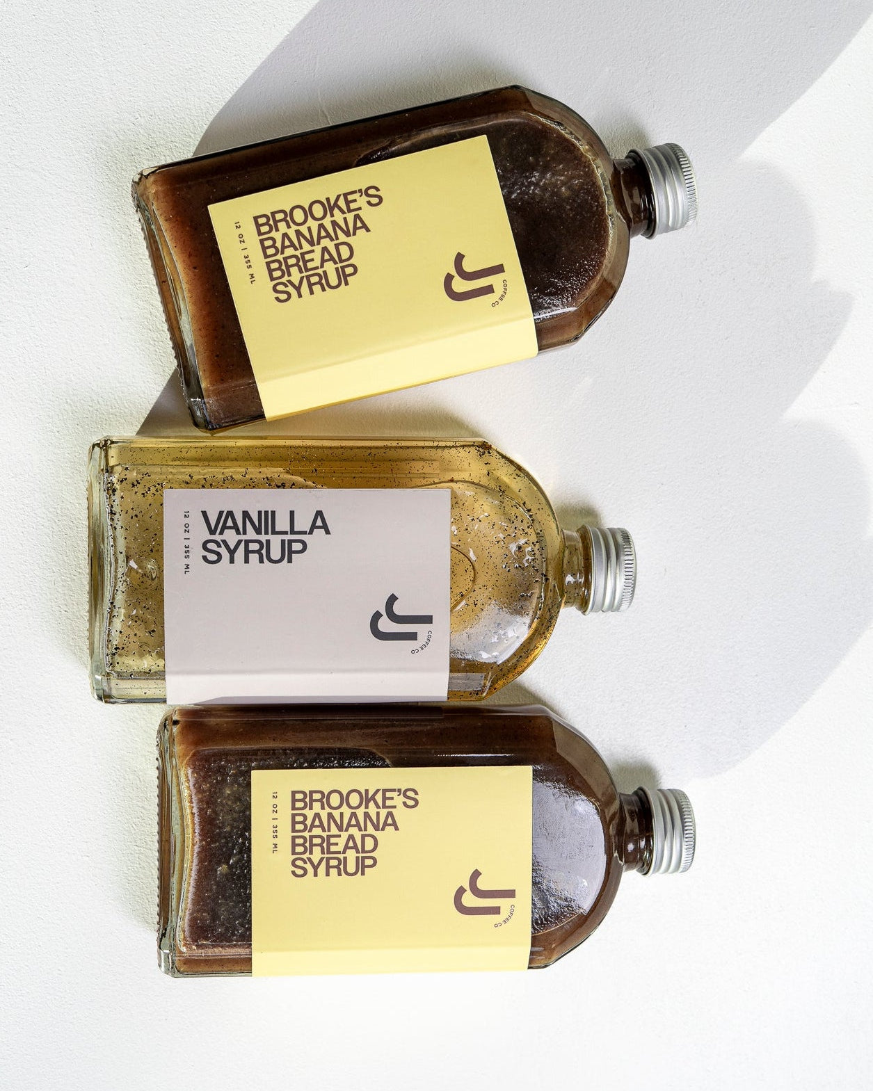 Three bottles of JJ's Syrup on a white background